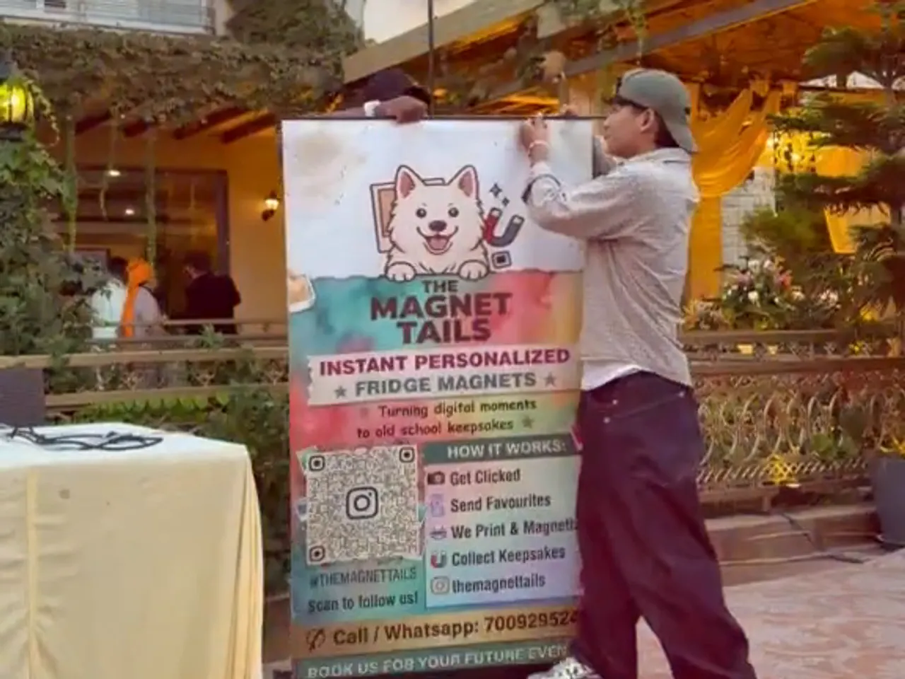 A crew member setting up the stall banner in the venue courtyard before guests arrive