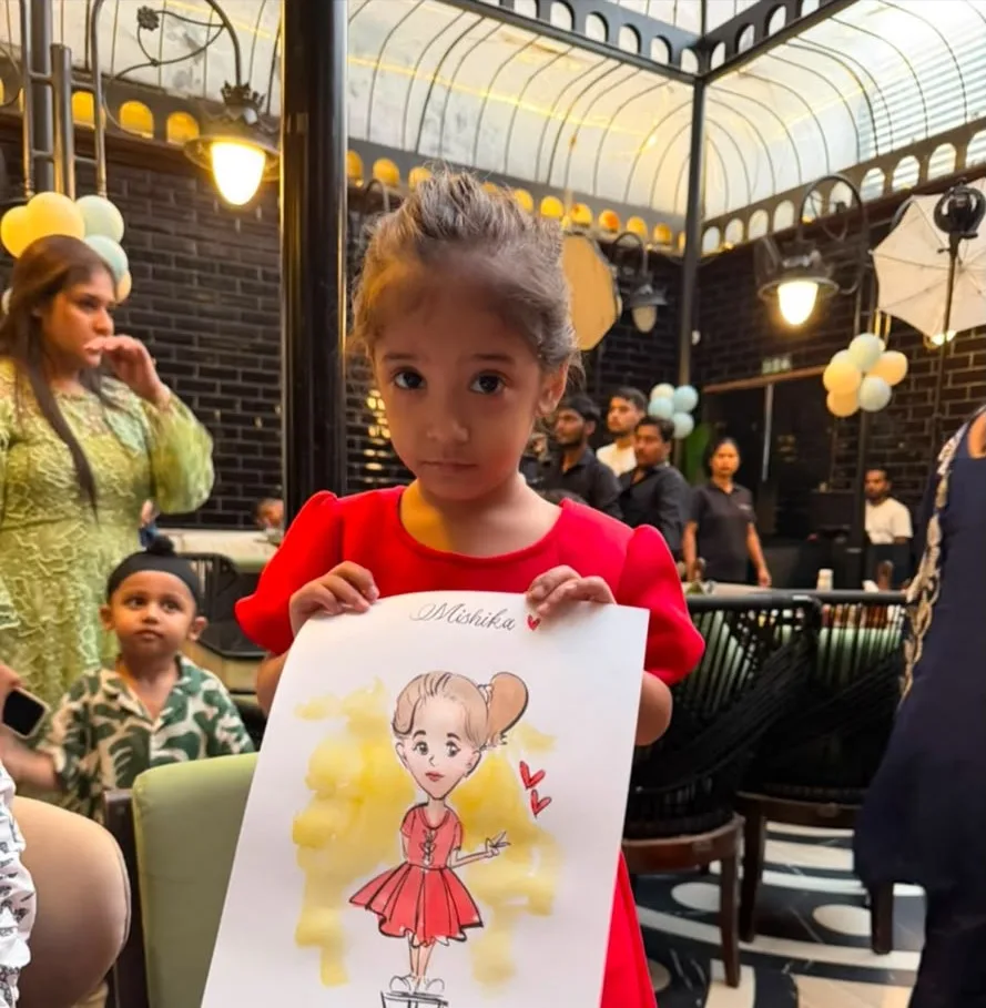 A girl in a red dress holding up a full-length caricature of herself at an indoor venue